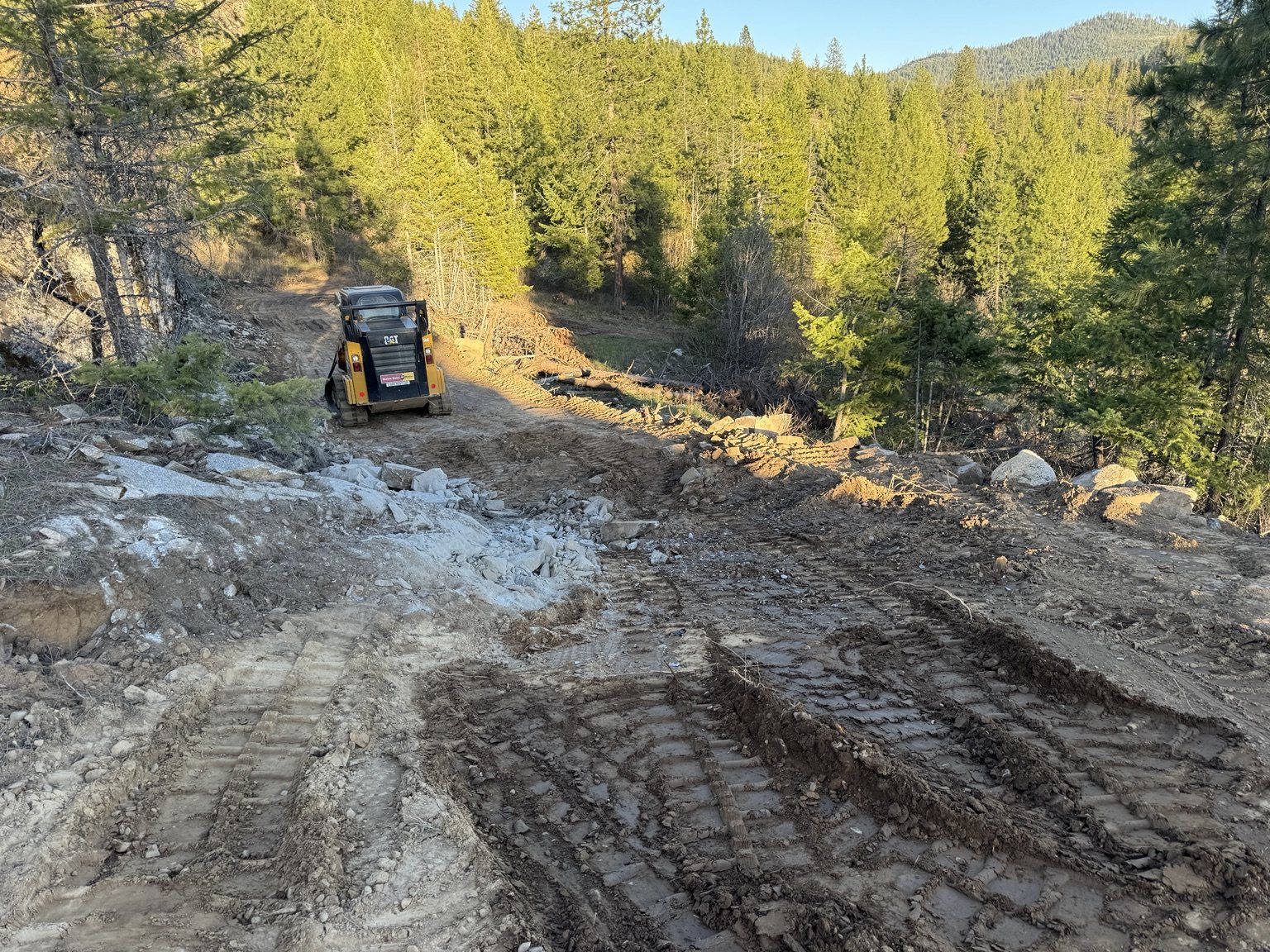 Compact track loader working on a rough North Idaho access route